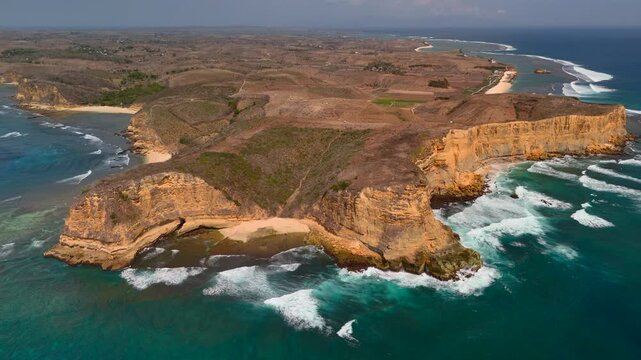 Aerial view of rugged coastal cliffs turquoise ocean waves sandy coves and dry plateau Scenic tropical shoreline with dramatic rock formations surf beaches and remote natural landscape