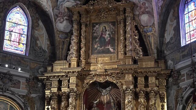 A direct upward view of the vibrant baroque frescoes and gold detailing on the vaulted ceiling of the historic parish church creating a breathtaking display of religious artistry