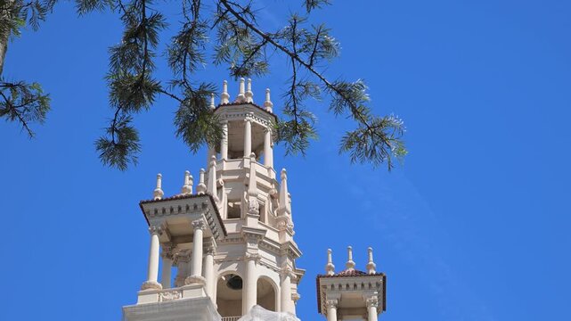 The ornate facade and iconic clock tower of the historic building stand prominently against a clear blue sky in the city centre during a bright afternoon