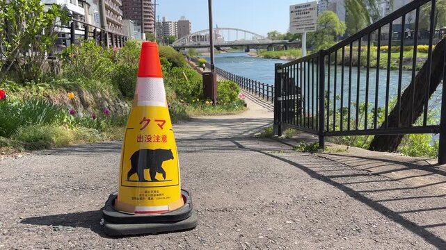 Traffic cone with bear warning sign (&ldquo;Beware of bears&rdquo;) along the Kitakami River in Morioka, Iwate Prefecture, Japan.