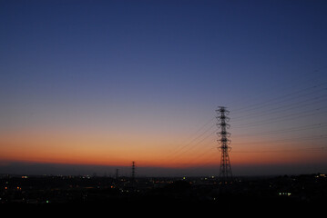 Fototapeta premium Sunset Gradient over Transmission Towers and City Lights