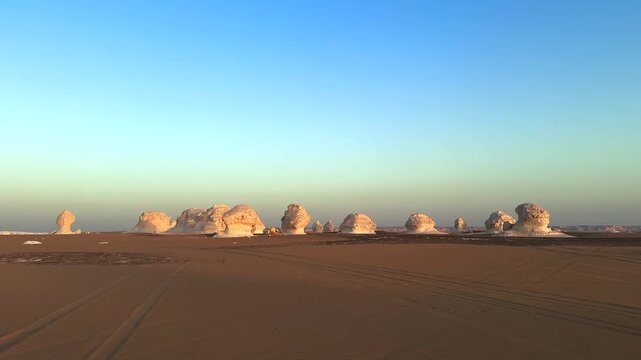 White desert landscape with limestone formations on the sand dunes at sunset