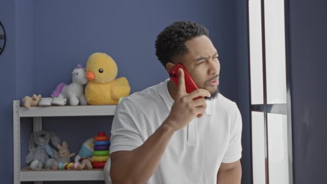 Man holding red smartphone to ear while peering out window in nursery with toys on shelf; concern alertness.