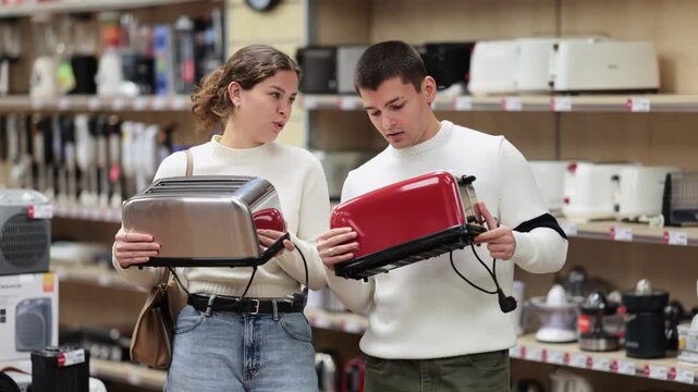  Young couple man and woman choosing electric toaster in home appliance store