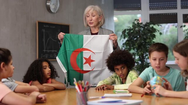 Female teacher showing algerian flag to kids in geography class