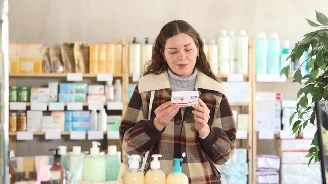 Young woman buyer chooses box of paracetamol tablets in pharmacy