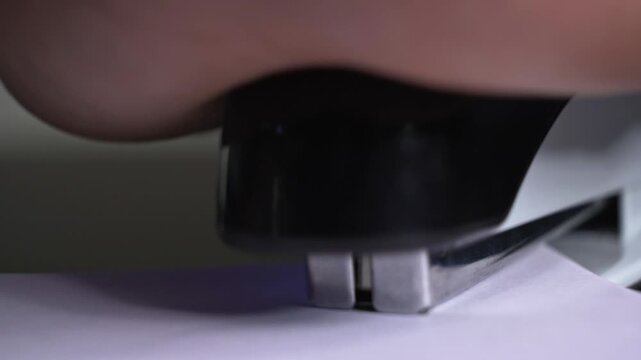 Extreme macro front view of a stapler mechanism pressing blank paper