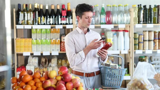 Man scans the barcode from a package of ketchup on his phone and pays for it using an online application. High quality 4k footage