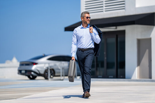 Corporate business. Rich businessman suit. Business success. Successful businessman walking with briefcase. Businessman hold briefcase. Confident businessman in suit after successful deal