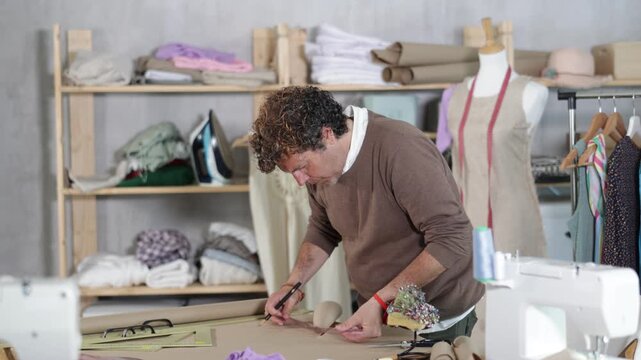 Man tailor draw dress pattern of product on paper. Craftsman perform paper prototype of product parts, drawing paper pattern for dressmaking.