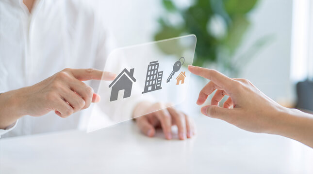Hands pointing at with house building and key property icons on table. Real estate agent and client selection digital interface. Home buying renting and housing investment service with handover