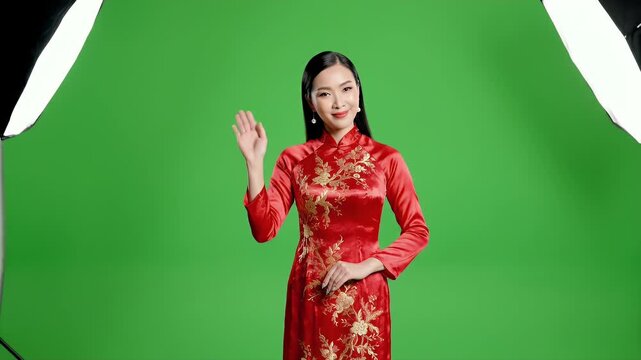 Elegant Vietnamese Woman in Traditional Red Ao Dai Dress Waving Hello Green Screen Background Studio Lighting Detailed Gold Embroidery