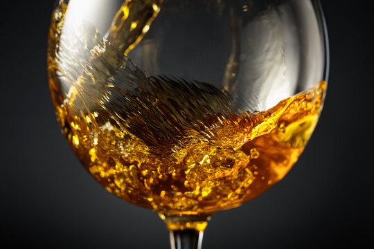 White wine of rich amber color being poured into a glass.