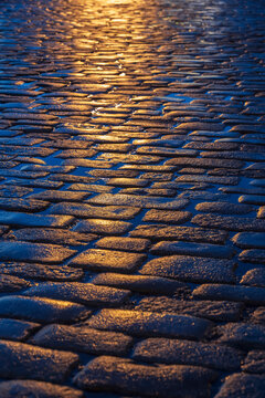 Wet cobblestone pavement reflecting light after rain at night