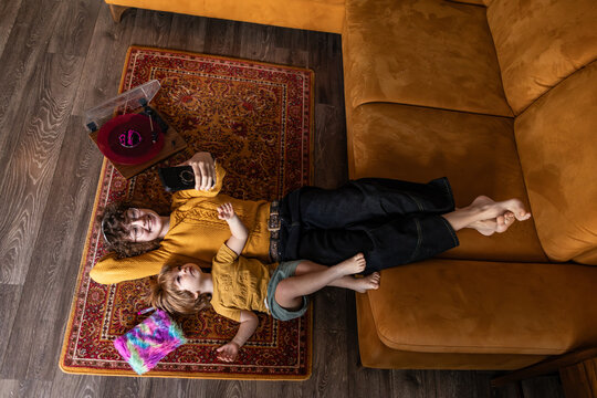 Siblings relaxing on floor with smartphone and vinyl record