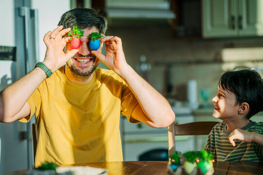 Father and son playing with Easter egg microgreens in kitchen