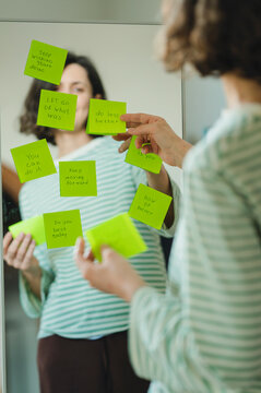 Woman reading positive affirmations on a mirror indoors