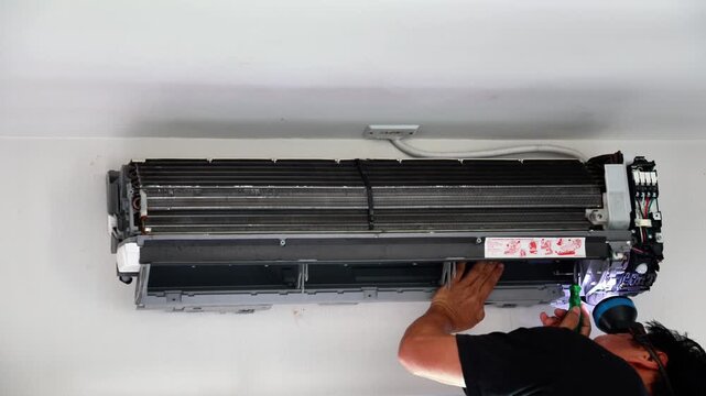 Professional technician disassembling and carefully reassembling a wall-mounted air conditioner blower fan during a deep cleaning and maintenance service.