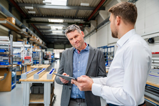Managers discussing business planning with tablet in factory