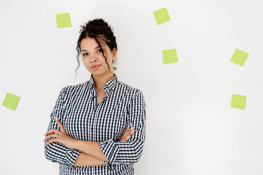 Smiling businesswoman with crossed arms near adhesive note