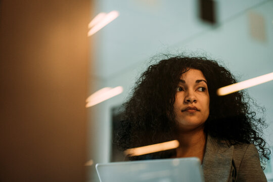 Thoughtful businesswoman with curly hair working at office