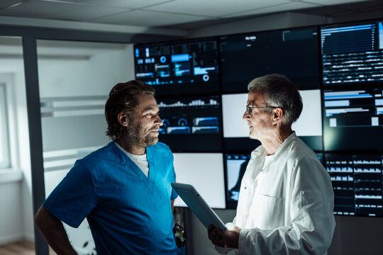 Doctor and colleague analyzing AI data on tablet during overtime