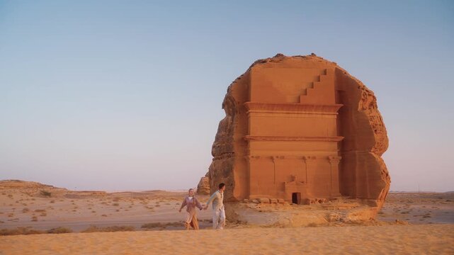 Discovering Saudi Arabia, traveling to AlUla and visiting Hegra. Tourists married couple enjoy view of ancient tombs in Al Ula.
