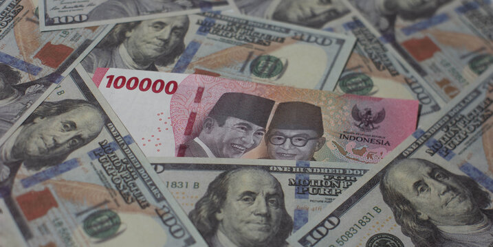 A Jumble of mixed Paper Currency banknotes, including US Dollars and Indonesian Rupiah. For Business, Financial, Wealth, Investment, Exchange Dollar and Rupiah Currency Concept.