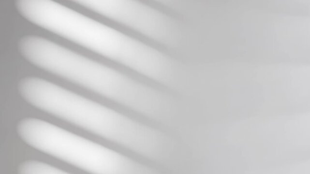 Minimalist white wall backdrop with soft shadow patterns creates elegant modern studio space for product photography and presentation displays with clean aesthetic.