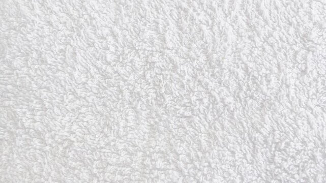 Soft white towel with fluffy cotton texture on grey background. Perfect bathroom or spa mockup template for design projects and product presentations.