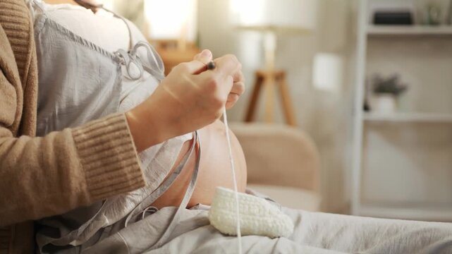 Close-up of a pregnant woman knitting baby booties for mindfulness and stress relief at home.
