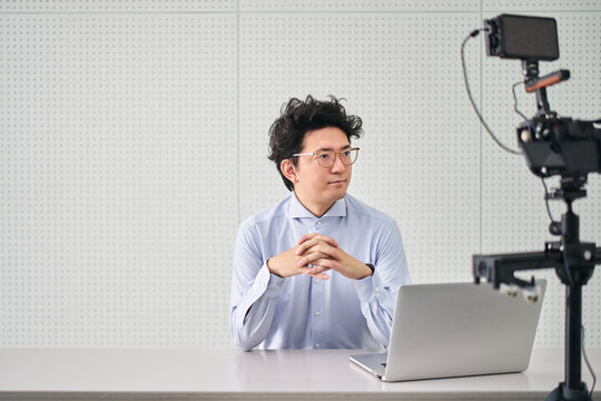 カメラとパソコンを使って小規模のニュースや情報を発信する解説者の男性