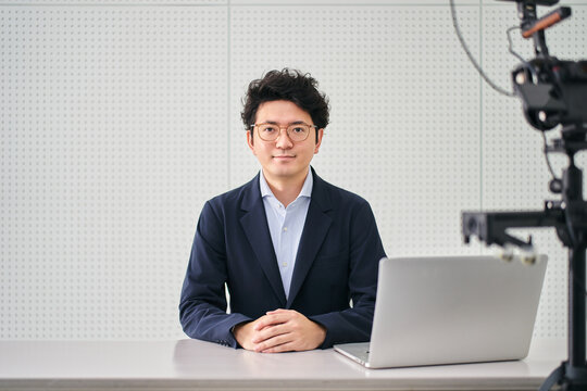 撮影スタジオでニュースの配信をする30代のフリーのアナウンサーの男性