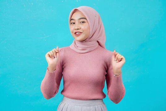 Happy Young Muslim Woman Wearing Hijab Dancing on Blue Background