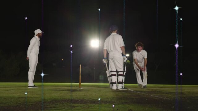 Cricket bowler delivering ball batsman reacting fielder picking ball restarting play lights flaring