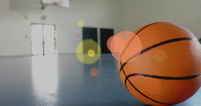 Resting orange basketball sitting on shiny blue court at gym, hoop visible, copy space