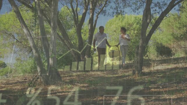 Couple walking downhill for picnic carrying basket as approaching lens, data graphs % appearing