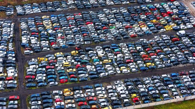 Overhead shot of dense rows of dismantled scrap cars. Close up aerial view showing various wrecked vehicles in a salvage yard during the recycling process.
