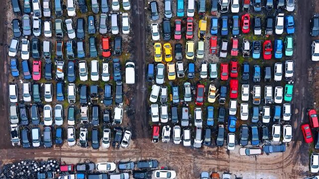 Top down view of scrap car yard with tires. Aerial perspective showing wrecked vehicles and a pile of used tires at an automotive recycling site.