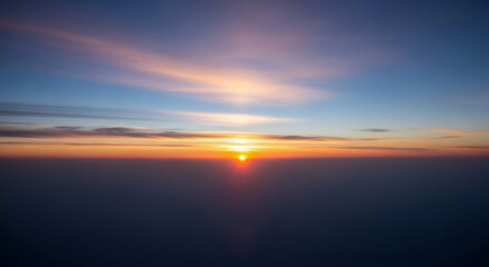 Fototapeta premium Vibrant sunset with orange sun and clouds in blue sky above sea or ocean horizon