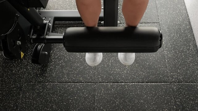 Woman performing seated leg extension exercise on machine, quadriceps workout in modern gym