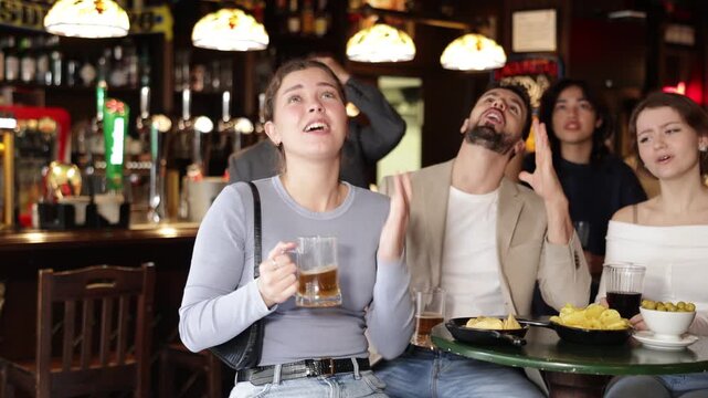 Group of men and women are sitting in a sports bar and watching a game, they are upset about the teams loss. High quality 4k footage
