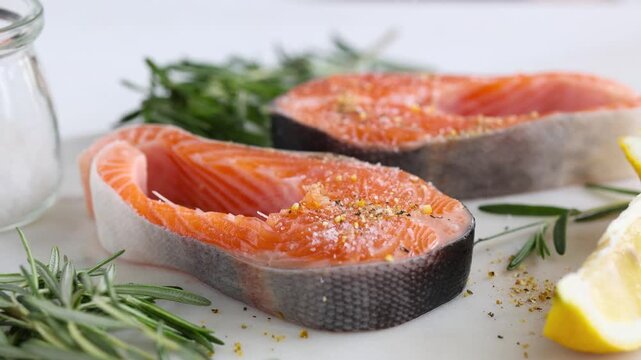 Preparation of salmon steak for grill. Sprinkling sea salt over red fish salmon. Cooking process