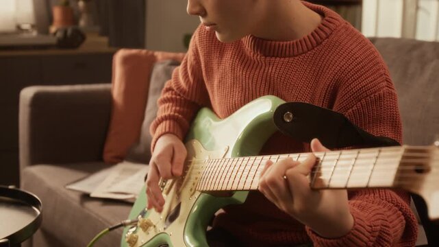 Side view talented young boy playing electric guitar at home with focus flowing from face to hands on strings scene lit by warm cinematic lighting, copy space Useful for emotional visuals