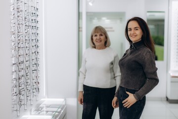 Women visiting optical store choosing new glasses for vision