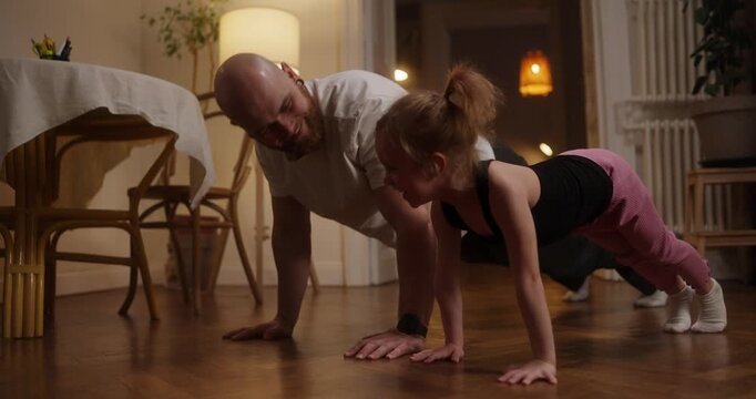 A dad and daughter enjoy happy moments doing push-ups, creating joyful memories together