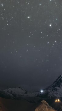 Stepantsminda, Georgia. Peak Of Mount Kazbek Covered With Snow, Famous Gergeti Church And Countryside Houses In Night Lightning. Georgian Landscape