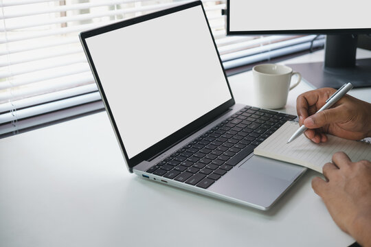 Remote work note taking with laptop and notebook on clean desk, planning and writing ideas in modern workspace, productivity and business workflow organization concept