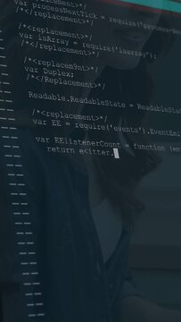 Vertical video: Woman coding at desk, causing code overlay scrolling and filling frame for project