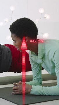 Vertical video: Lady holding plank on mat watching partner moving as red arrows updating fitness